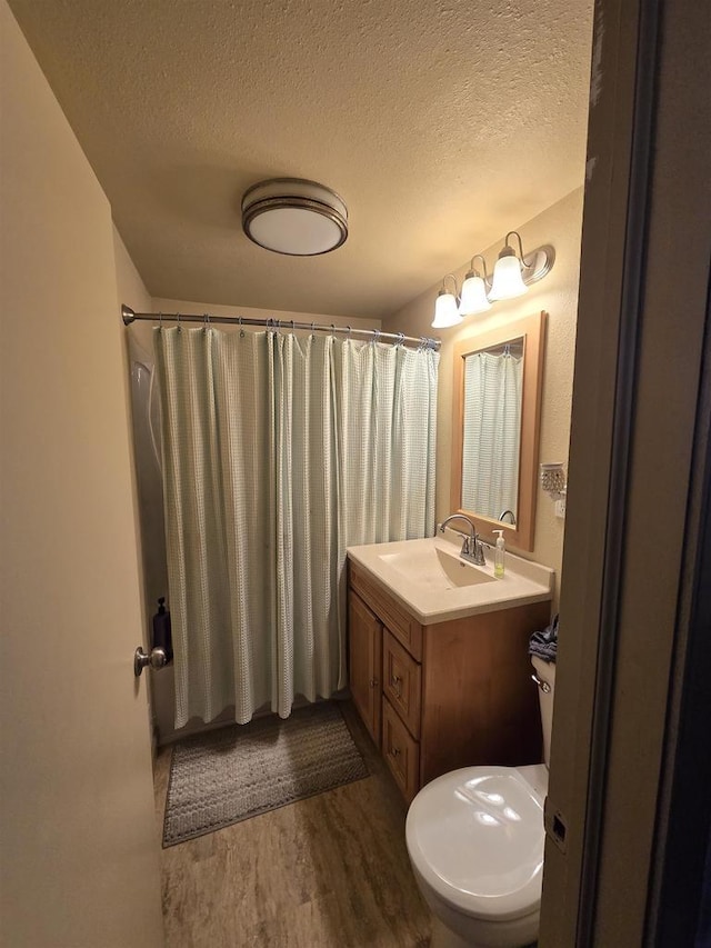 bathroom featuring curtained shower, a textured ceiling, wood finished floors, and vanity