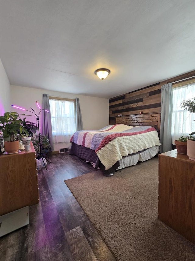 bedroom featuring visible vents, wood walls, and wood finished floors