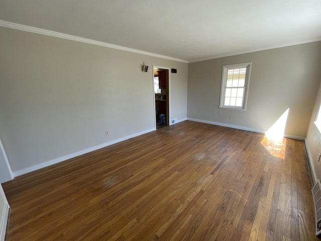 empty room with dark wood-style floors, baseboards, and ornamental molding