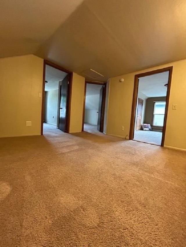 unfurnished room featuring carpet flooring and vaulted ceiling