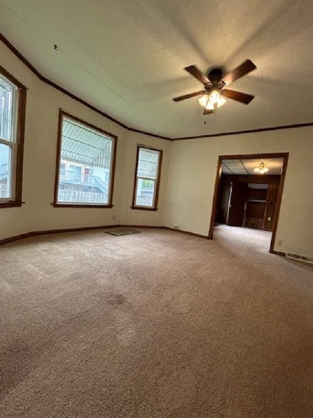 spare room featuring baseboards, light colored carpet, ornamental molding, and a ceiling fan