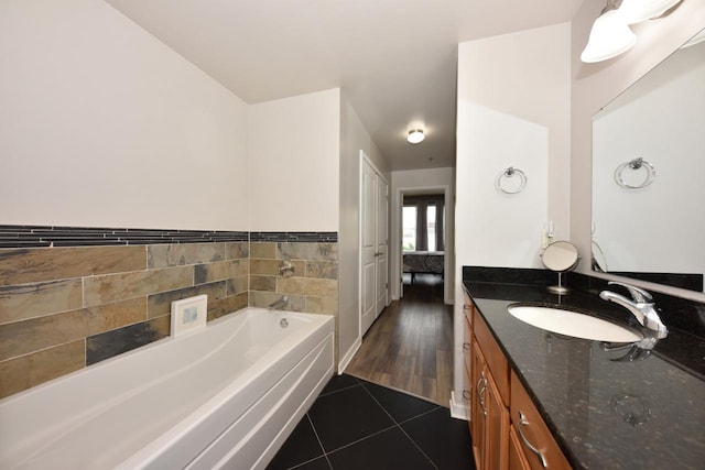 ensuite bathroom featuring connected bathroom, a bath, vanity, and tile patterned flooring