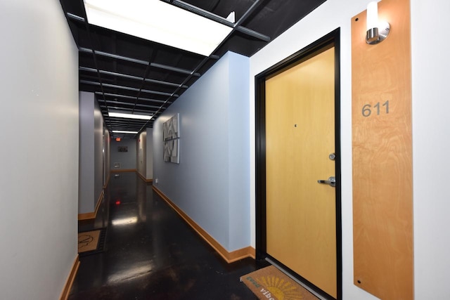 hallway featuring finished concrete flooring and baseboards