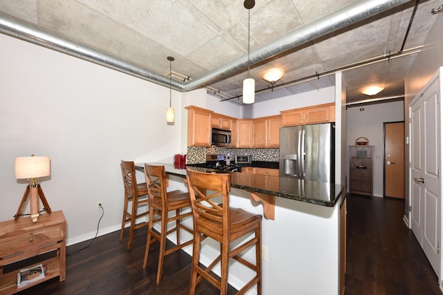 kitchen featuring pendant lighting, a breakfast bar, decorative backsplash, dark wood-style floors, and stainless steel appliances