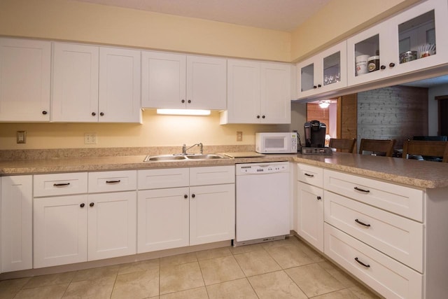 kitchen featuring white appliances, a peninsula, a sink, glass insert cabinets, and white cabinetry