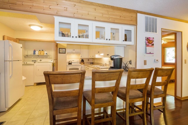 kitchen with visible vents, washer and clothes dryer, a peninsula, white appliances, and a sink