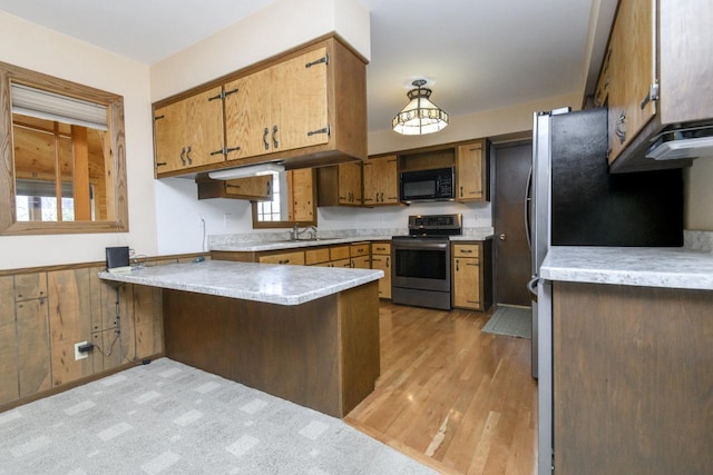 kitchen featuring a sink, a peninsula, black microwave, light countertops, and stainless steel electric range oven