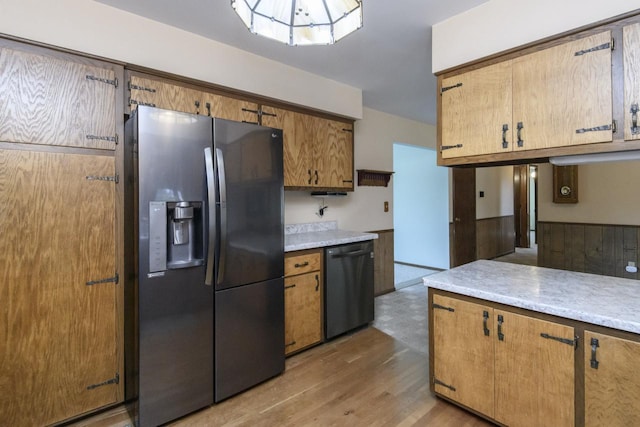 kitchen featuring stainless steel refrigerator with ice dispenser, black dishwasher, wood finished floors, brown cabinetry, and light countertops