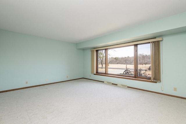 carpeted spare room featuring visible vents and baseboards