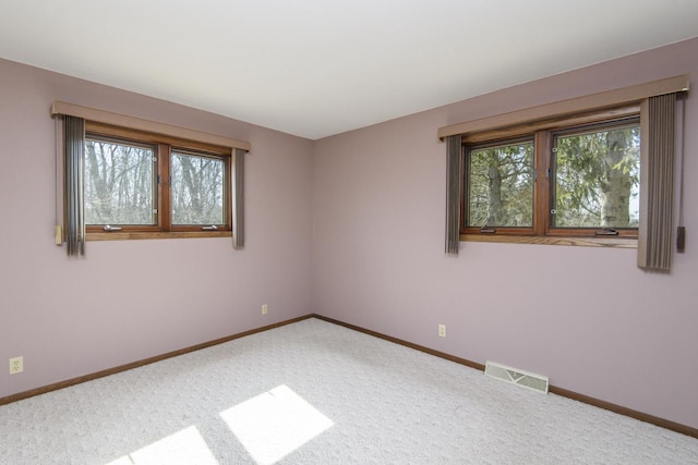 carpeted empty room with a wealth of natural light, visible vents, and baseboards