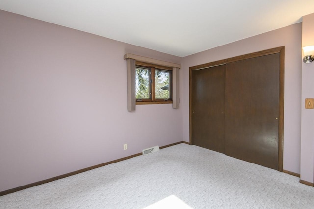 unfurnished bedroom with carpet flooring, baseboards, visible vents, and a closet