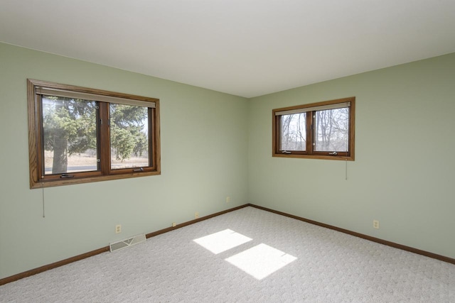 unfurnished room with visible vents, plenty of natural light, baseboards, and carpet