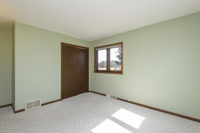 unfurnished bedroom with a closet, visible vents, carpet flooring, and baseboards