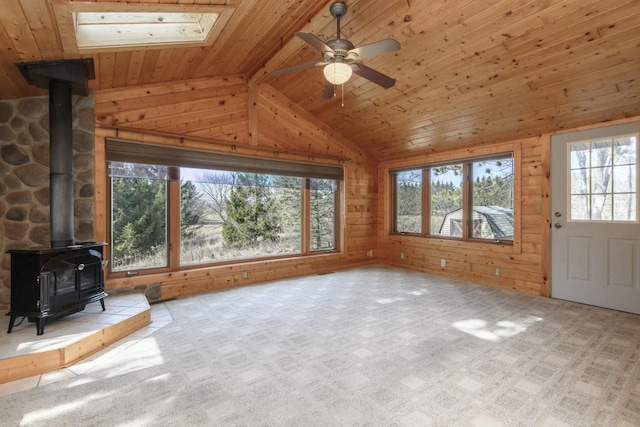 unfurnished living room with lofted ceiling with beams, a wood stove, wood ceiling, and wood walls