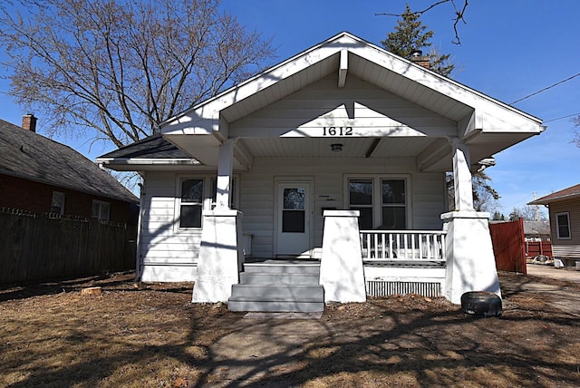 bungalow-style home with a porch and fence