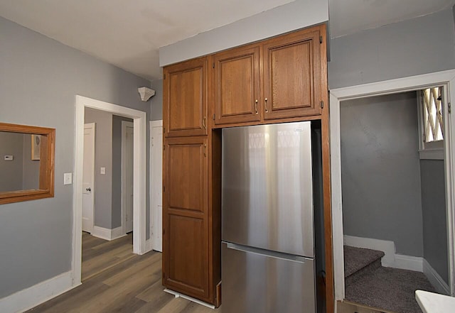 kitchen with baseboards, dark wood finished floors, brown cabinetry, and freestanding refrigerator