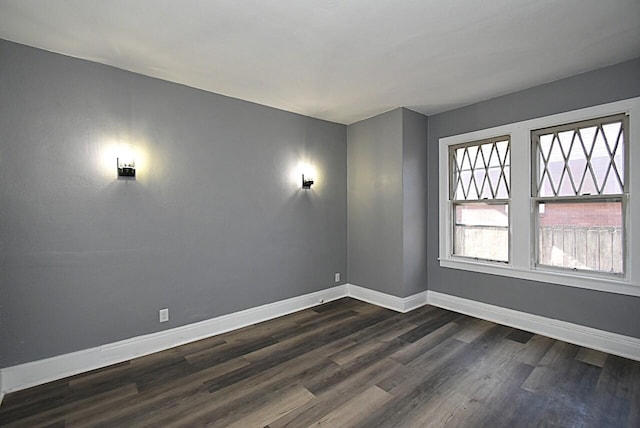 spare room featuring dark wood-style floors and baseboards