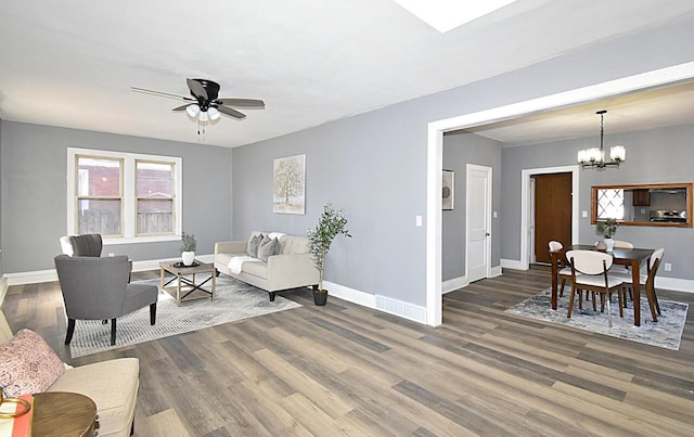 living room with wood finished floors, ceiling fan with notable chandelier, and baseboards