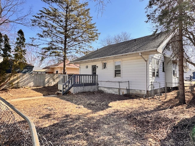 back of property featuring a shingled roof, fence, and a wooden deck