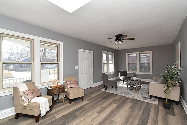 living area featuring ceiling fan, baseboards, and wood finished floors