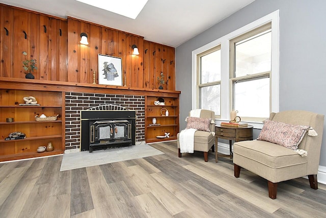 living area with wooden walls, a tile fireplace, and light wood-type flooring