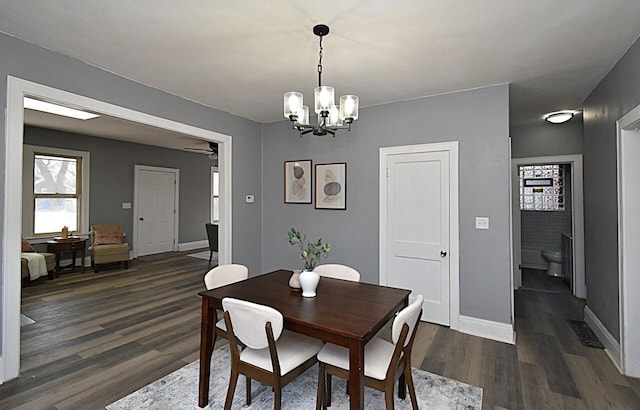 dining room featuring ceiling fan with notable chandelier, baseboards, and dark wood-style flooring