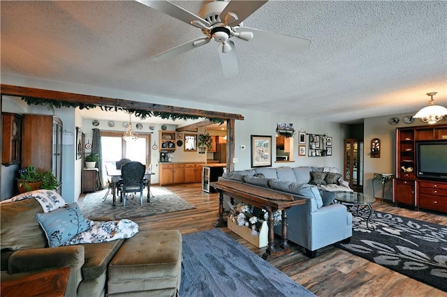 living room with ceiling fan with notable chandelier, wood finished floors, and a textured ceiling