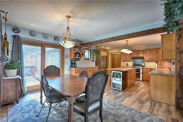 dining space with beamed ceiling, a textured ceiling, and light wood finished floors