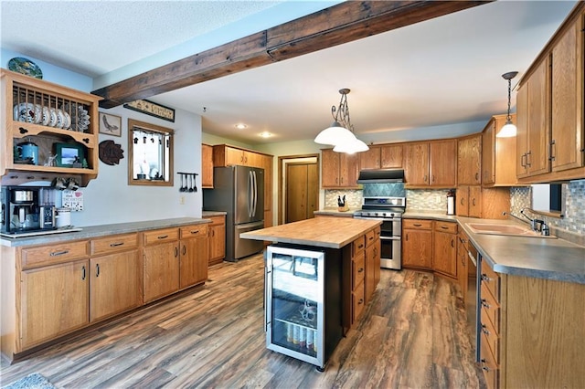 kitchen with a kitchen island, under cabinet range hood, dark wood finished floors, stainless steel appliances, and a sink