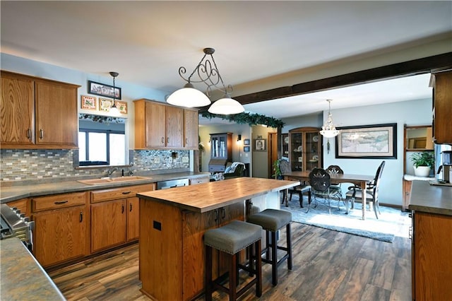 kitchen featuring a sink, dark wood-style floors, appliances with stainless steel finishes, butcher block counters, and decorative backsplash