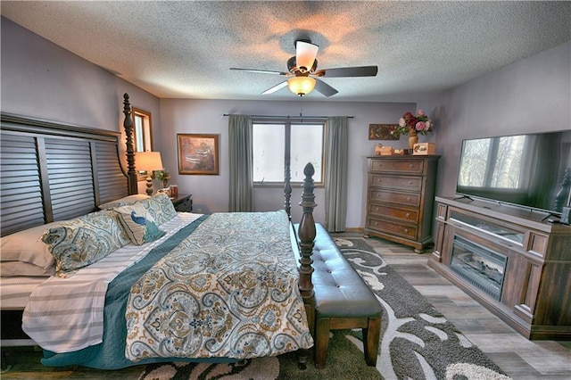 bedroom with a textured ceiling, light wood-type flooring, and ceiling fan