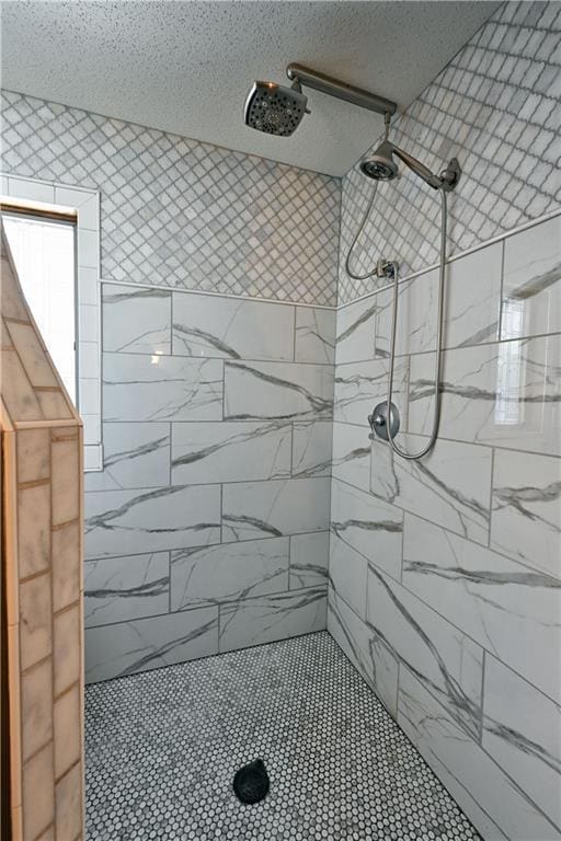 bathroom with a textured ceiling and a tile shower