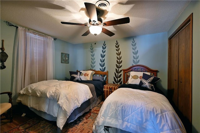 bedroom featuring a closet, wood finished floors, a textured ceiling, and ceiling fan