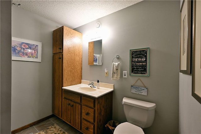 bathroom with tile patterned flooring, a textured ceiling, toilet, and vanity