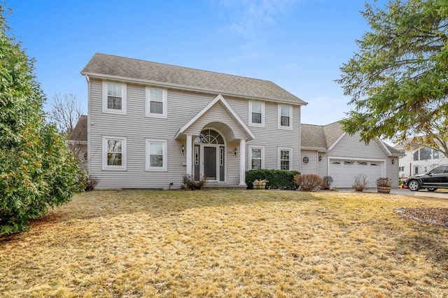 colonial home featuring a front lawn, an attached garage, and a shingled roof