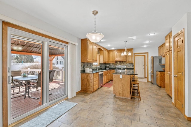 kitchen featuring decorative backsplash, appliances with stainless steel finishes, dark countertops, a notable chandelier, and a center island