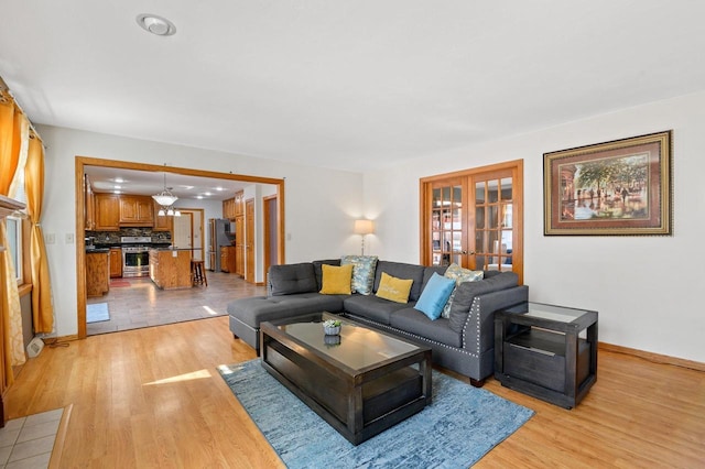 living room featuring light wood-style flooring, french doors, and baseboards