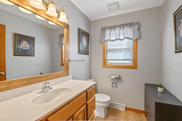 bathroom with visible vents, baseboards, toilet, wood finished floors, and vanity