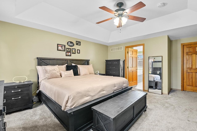 bedroom with visible vents, ceiling fan, baseboards, light carpet, and a raised ceiling