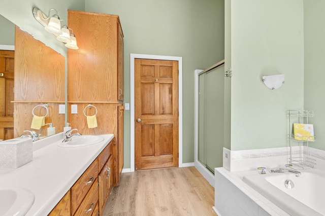 bathroom with a sink, a garden tub, wood finished floors, and a shower stall