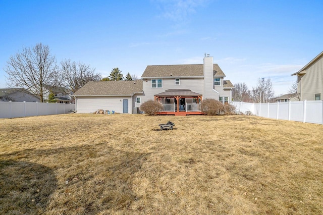 rear view of property featuring a fenced backyard, a shingled roof, a chimney, a gazebo, and a lawn