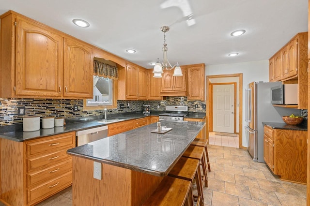 kitchen with a kitchen bar, a sink, a kitchen island, backsplash, and appliances with stainless steel finishes