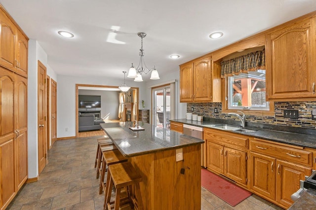 kitchen featuring a sink, a kitchen bar, dishwasher, backsplash, and a center island