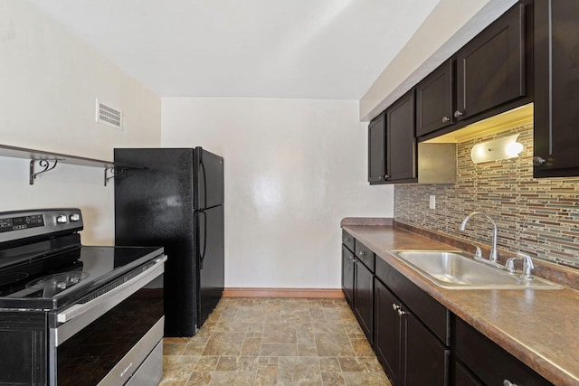 kitchen featuring visible vents, stainless steel range with electric stovetop, a sink, freestanding refrigerator, and decorative backsplash