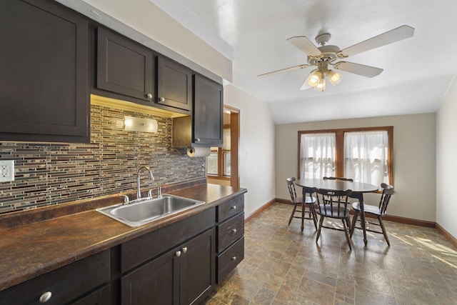 kitchen featuring backsplash, stone finish flooring, baseboards, a ceiling fan, and a sink