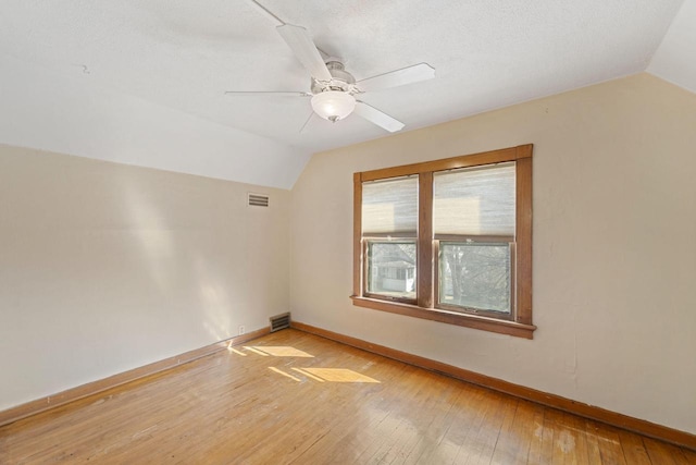 spare room featuring visible vents, baseboards, light wood-type flooring, and lofted ceiling