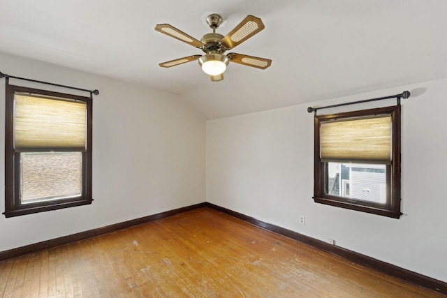 empty room with baseboards, hardwood / wood-style flooring, ceiling fan, and vaulted ceiling