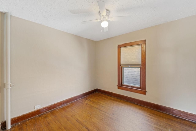 empty room with ceiling fan, baseboards, wood-type flooring, and a textured ceiling