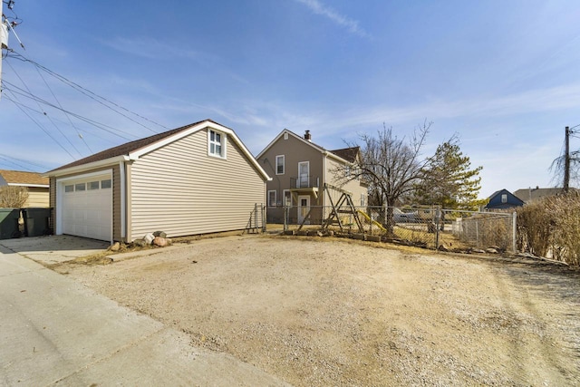 view of side of property featuring a detached garage, an outdoor structure, concrete driveway, and fence