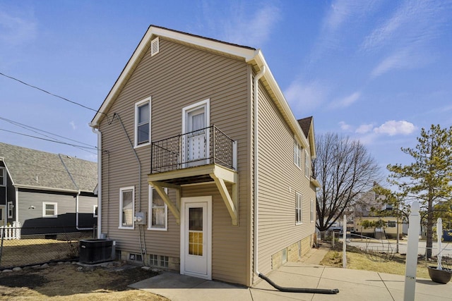 back of house with central AC unit, a balcony, and fence